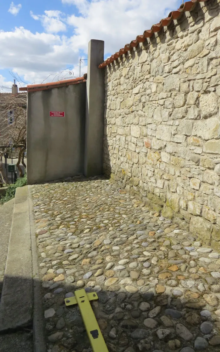 Private cobbled parking space along a stone wall