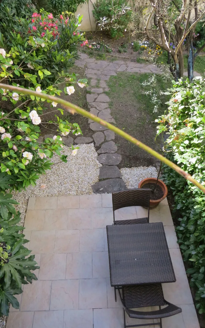 The studio's terrace seen from above, with table, chairs and flower garden