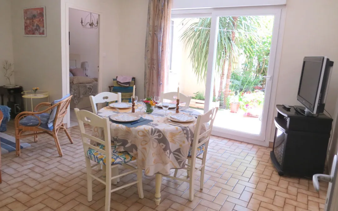 Sala de estar del apartamento: mesa puesta, zona de estar y ventanal que da al jardín