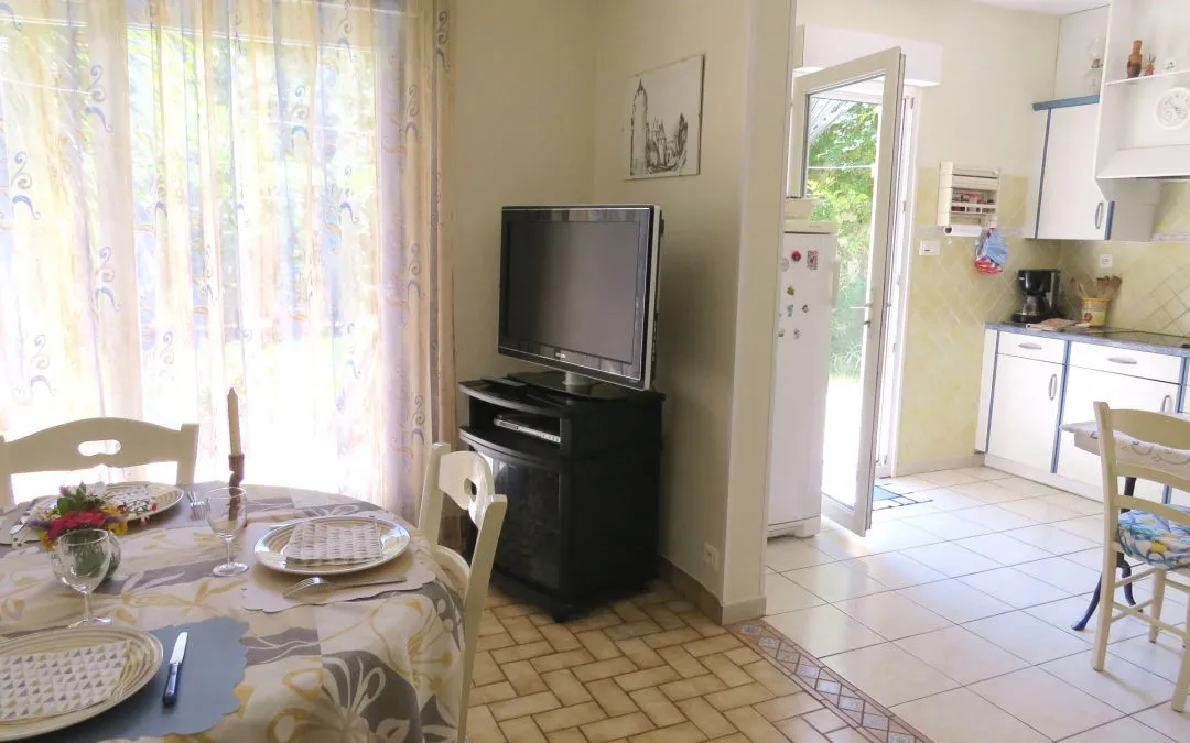 Comedor con televisión, abierto a la cocina y al jardín